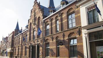 Een historisch gebouw met een opvallende klokkentoren en een bord met de tekst