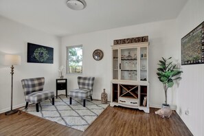 A living room with two plaid chairs, a floor lamp, a cabinet with glass doors, and a large plant.
