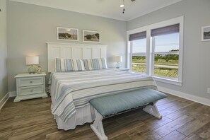 Ein Schlafzimmer mit einem großen Bett, zwei Nachttischen, einer Kopfteil und einem Fenster mit Blick ins Freie.