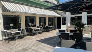 An outdoor patio area with tables and chairs, a covered seating area, and a sign for 'SWINCKELS'. - Peaceful Nature Stay Just Minutes from Lively Groningen Attractions! Pool! (Paterswolde)