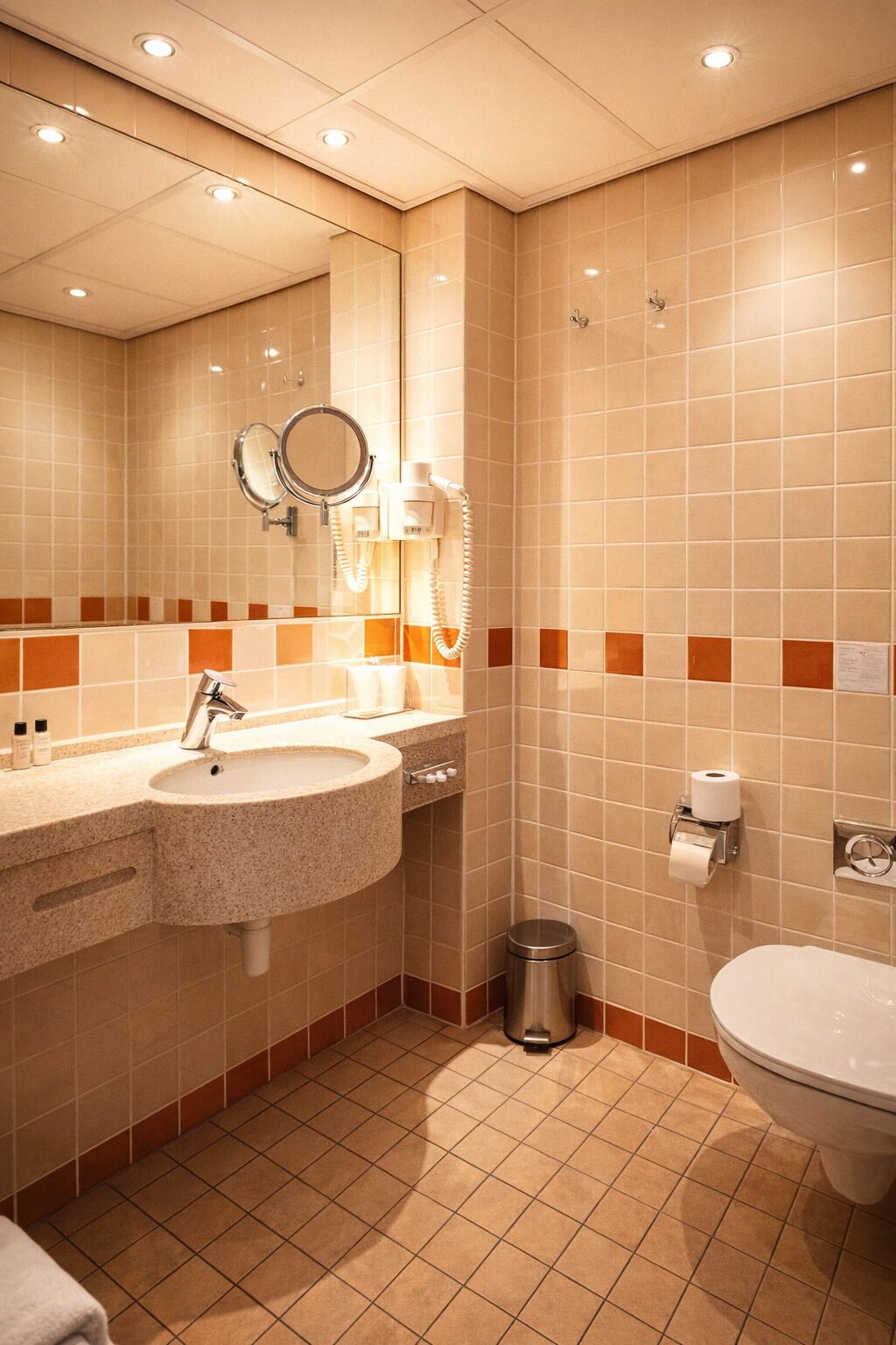 Ein Badezimmer mit Waschbecken, Spiegel, Toilette und Mülleimer.