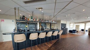 A bar area with a long counter, multiple stools, and a variety of bottles and glasses. - Relaxing Haamstede Haven | beach escape, Scenic Nature trails, Local attractions (Burgh-Haamstede)