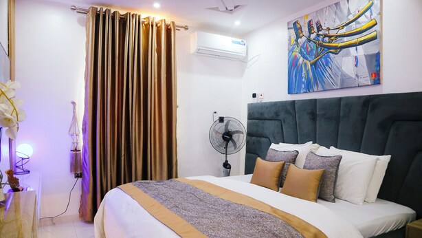 Hotellihuone, jossa on suuri sänky, kattotuuletin, ilmastointilaite ja taulu seinällä.