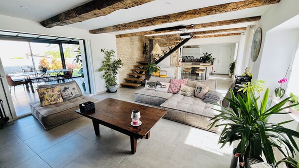 A spacious living area with a large sofa, a coffee table, and a staircase leading to an upper level.