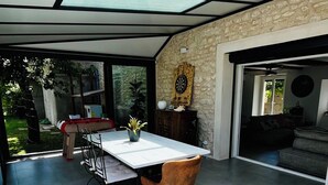 A spacious room with a large table and chairs, a potted plant, and a dartboard on the wall.