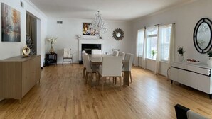 Amplia sala de estar con comedor, chimenea y un gran ventanal con cortinas.