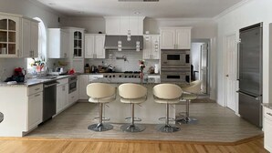 Una cocina moderna con armarios blancos, electrodomésticos de acero inoxidable y una isla central con taburetes de bar.