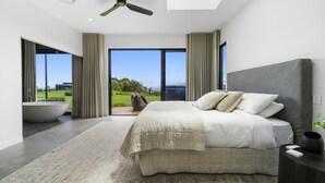 A modern bedroom with a large bed, a ceiling fan, and a view of the outdoors. - Scenic House With Private Yard & BBQ Area (Springbrook)