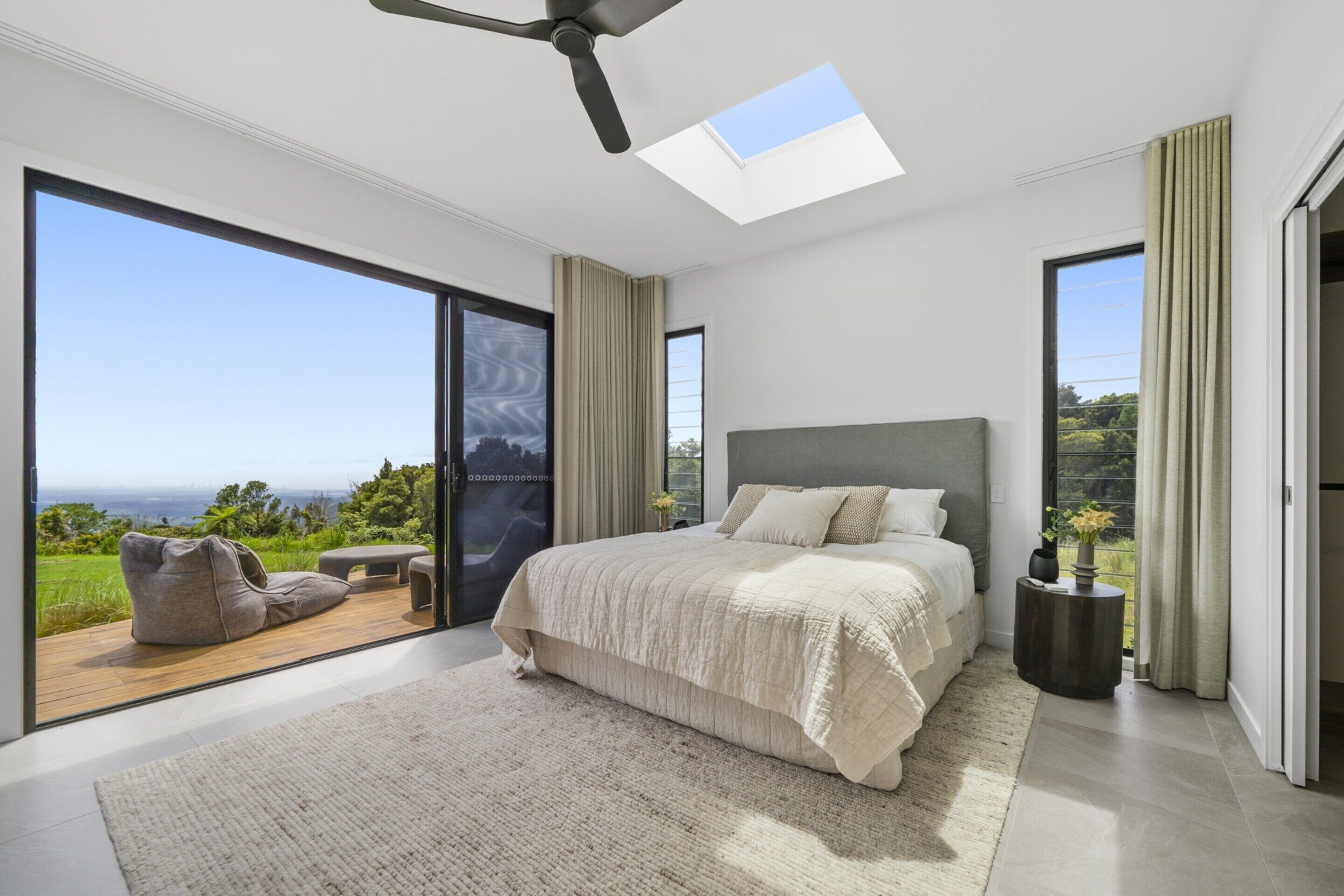 Un dormitorio moderno con una cama grande, un tragaluz y vistas al exterior.