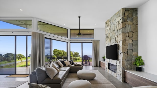 A modern living room with a large sectional sofa, a flat-screen TV, and a stone fireplace. - Scenic House With Private Yard & BBQ Area (Springbrook)