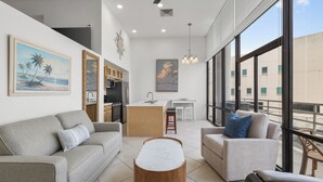 Een moderne woonkamer met een grijze bank, een houten salontafel en een balkon met uitzicht.