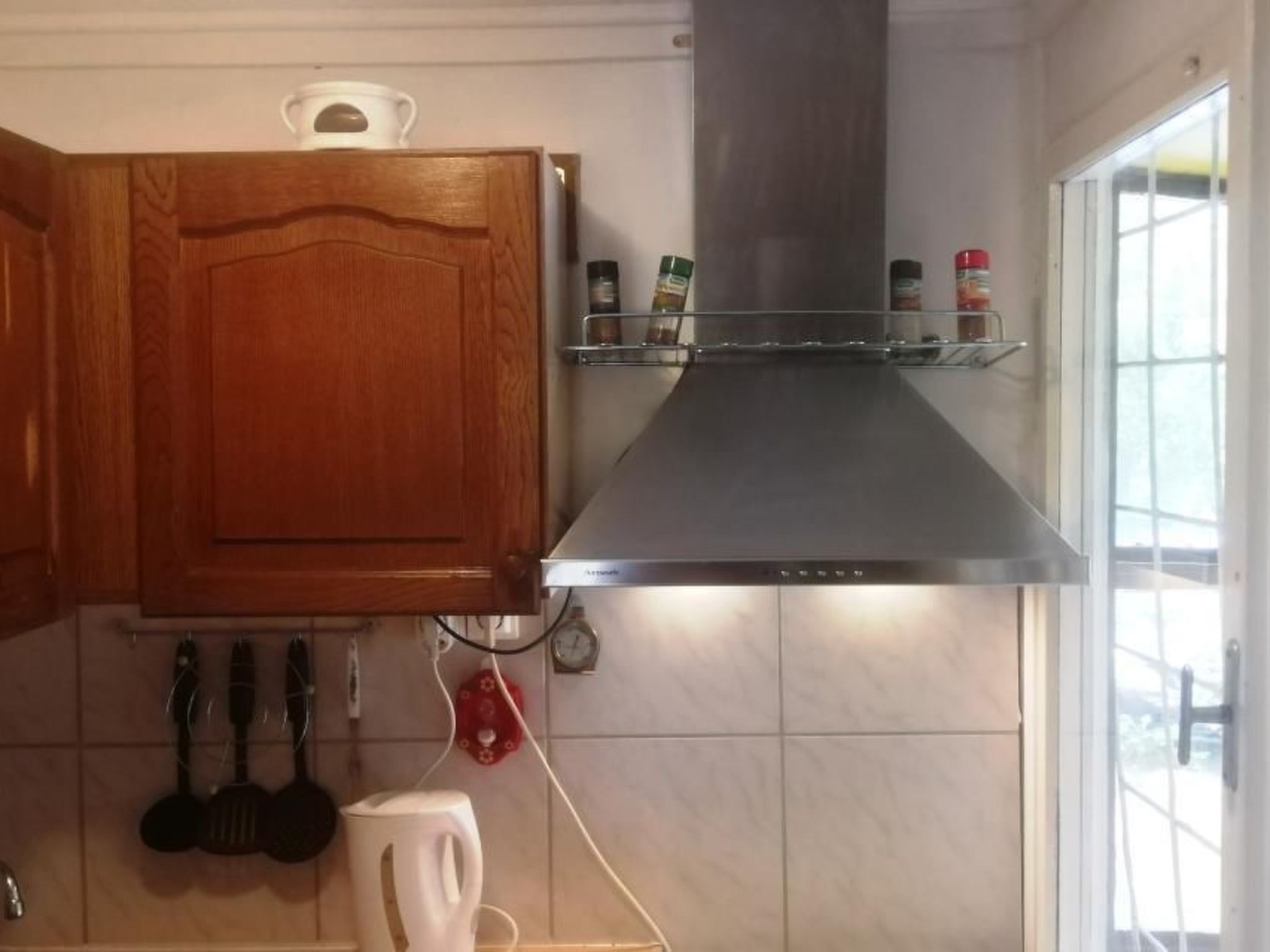 A kitchen with wooden cabinets, a stainless steel range hood, and a window with a view.