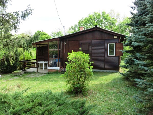 Une petite cabane en bois avec une véranda, une table et une chaise.