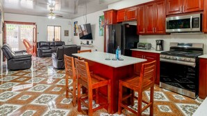 Uma sala de estar ampla com mesa de jantar, cozinha equipada com eletrodomésticos modernos e ventilador de teto.
