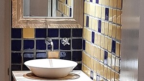 Ein Badezimmer mit einem weißen Waschbecken, Holzschränken und einer gefliesten Rückwand.