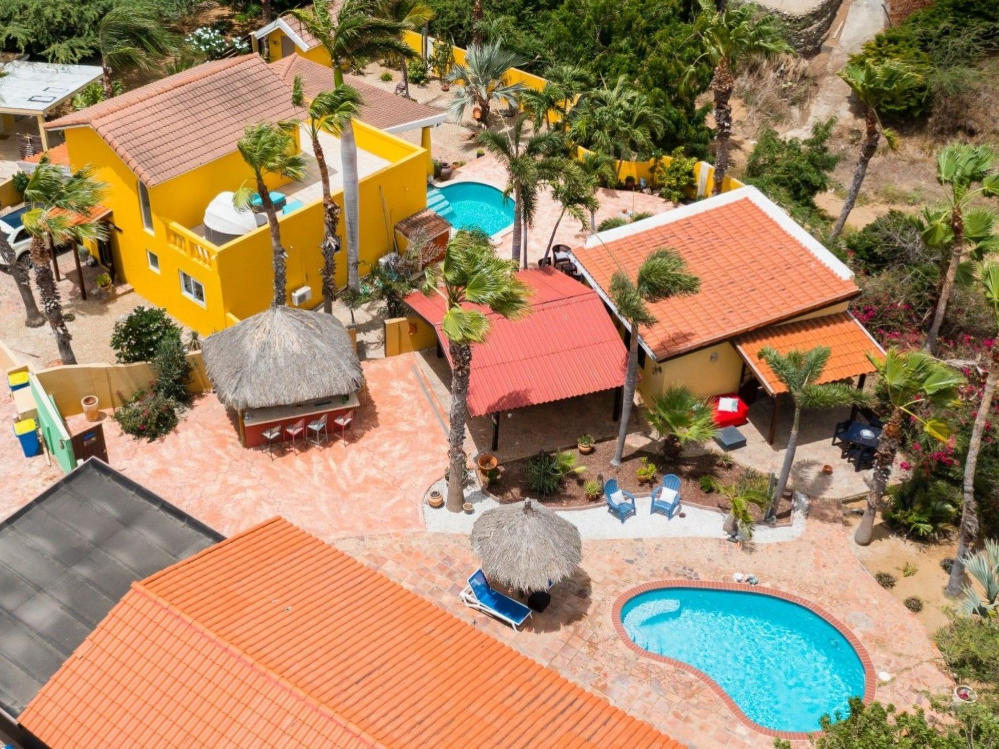 Ein Resort mit Swimmingpool, strohgedeckten Gebäuden und Palmen.