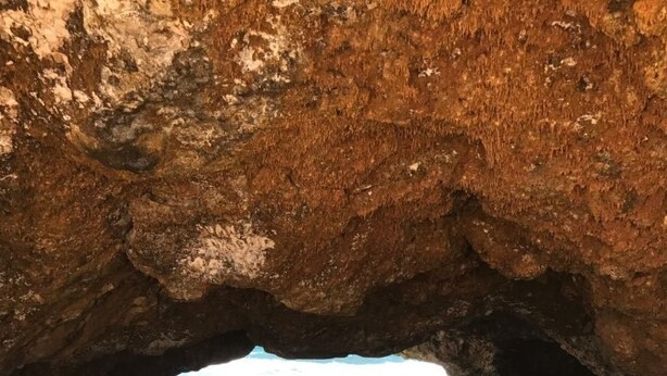 Ein Strand mit einer felsigen Höhle, die zum Meer führt.