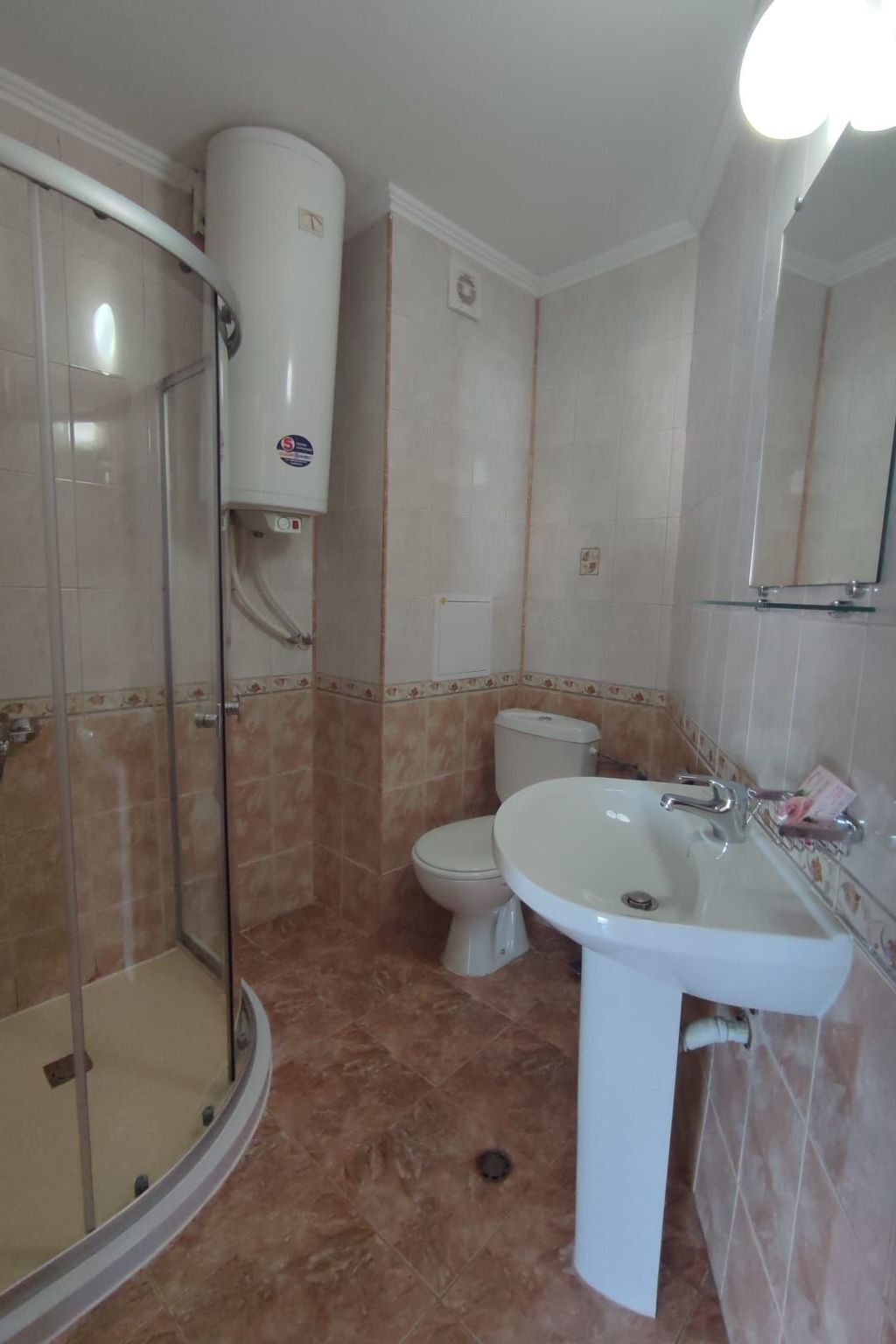 Ein Badezimmer mit Duschkabine aus Glas, Toilette und Waschbecken.