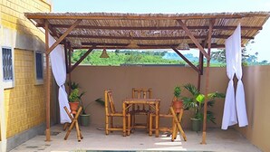 A swimming pool with checkered tiles, a wooden table with chairs, and potted plants. - Villa Macarena (Bonoua)