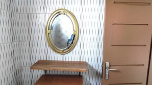 A room with a wooden cabinet, a mirror, and a door. - Villa Macarena (Bonoua)