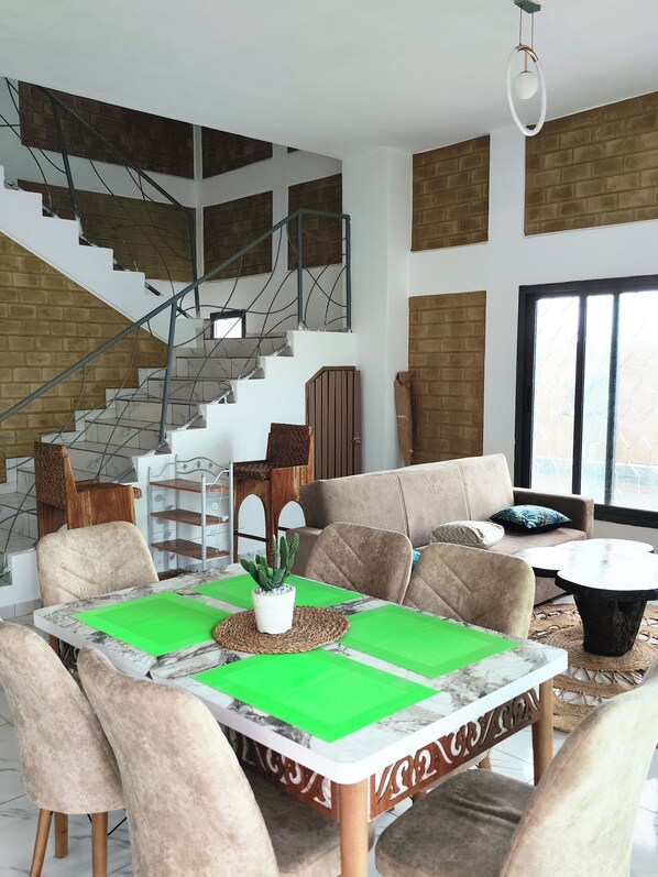 Una sala de estar moderna con una escalera, un comedor con mesa y sillas, y un sofá.