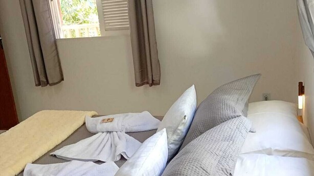 Ein Schlafzimmer mit einem Bett, Kissen, einer Decke und einem Fenster mit Vorhängen.