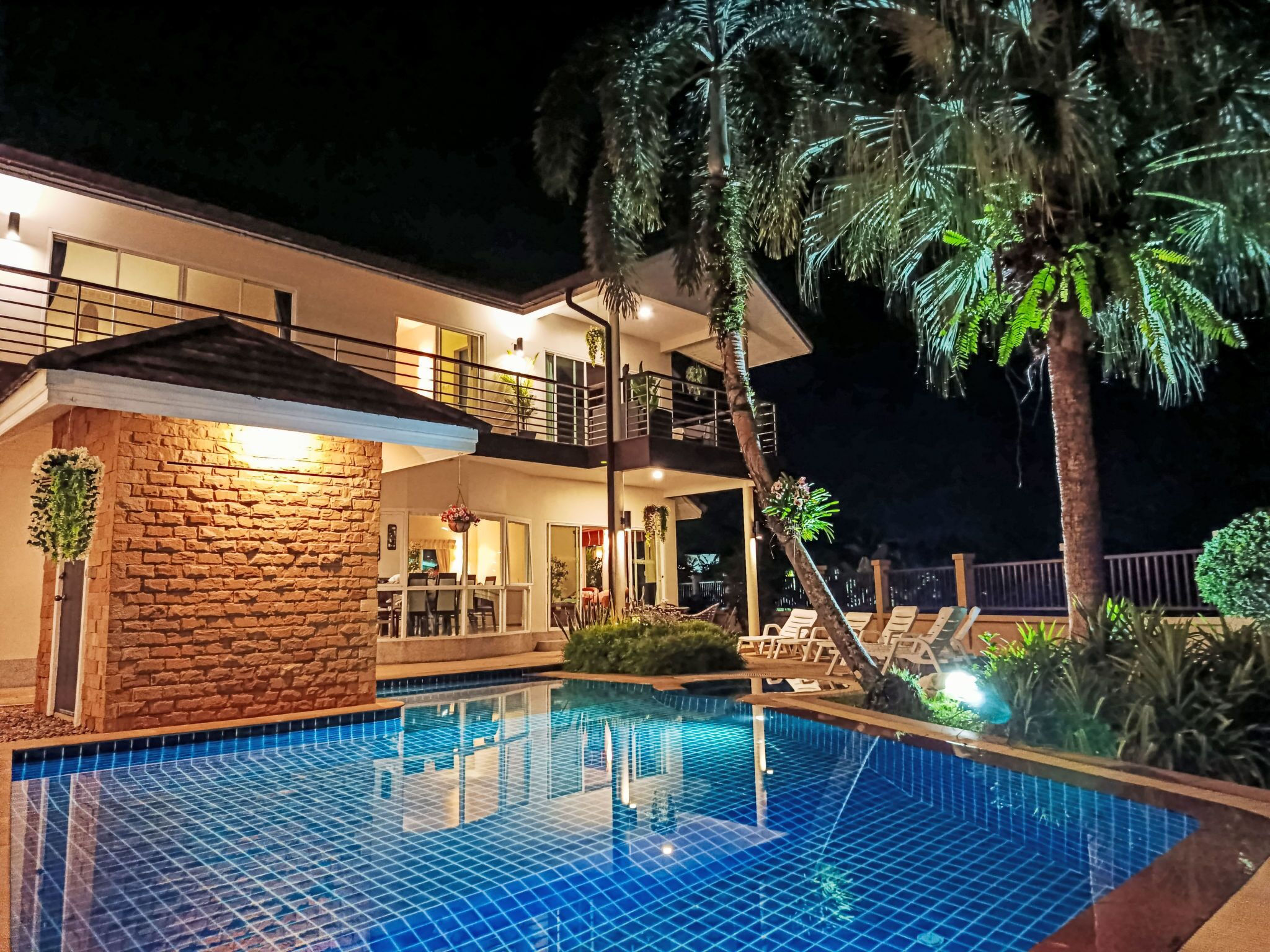 Une maison à deux étages dotée d’une piscine, d’un balcon et d’un éclairage extérieur soigné.