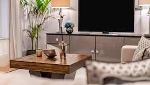 Ett modernt vardagsrum med ett soffbord i trä, en soffa, en tv och en krukväxt.