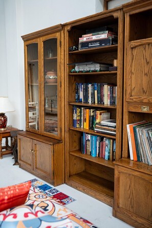 A wooden bookcase with multiple shelves filled with books and board games. - "Comfortably Off-Grid" by Interhome (Johannesburg)