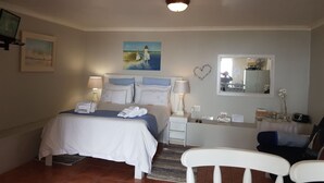 A hotel room with a bed, bedside tables, a desk, a chair, a mirror, and a painting on the wall. - Sunbirdview Gästehaus by Interhome (Langebaan)