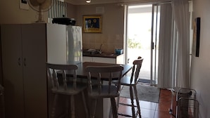 A kitchen with a refrigerator, a sink, and a dining area with chairs. - Sunbirdview Gästehaus by Interhome (Langebaan)