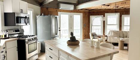 A kitchen with white cabinets, a stainless steel refrigerator, and a wooden ceiling.