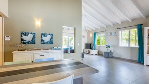 A spacious living area with a wooden dining table, white cabinets, and a TV. - Villa Drumi Dushi met privé zwembad by Interhome (Jan Thiel)