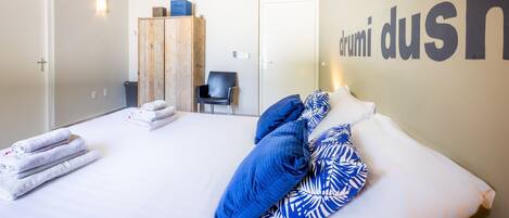 Habitación de hotel con cama, armario, silla y una pared con el texto "drumi dus".