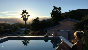 En swimmingpool med utsikt över ett berg och ett hus i bakgrunden.