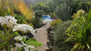 En tr ädgårdstig som leder till en pool med ett bergigt landskap i bakgrunden.