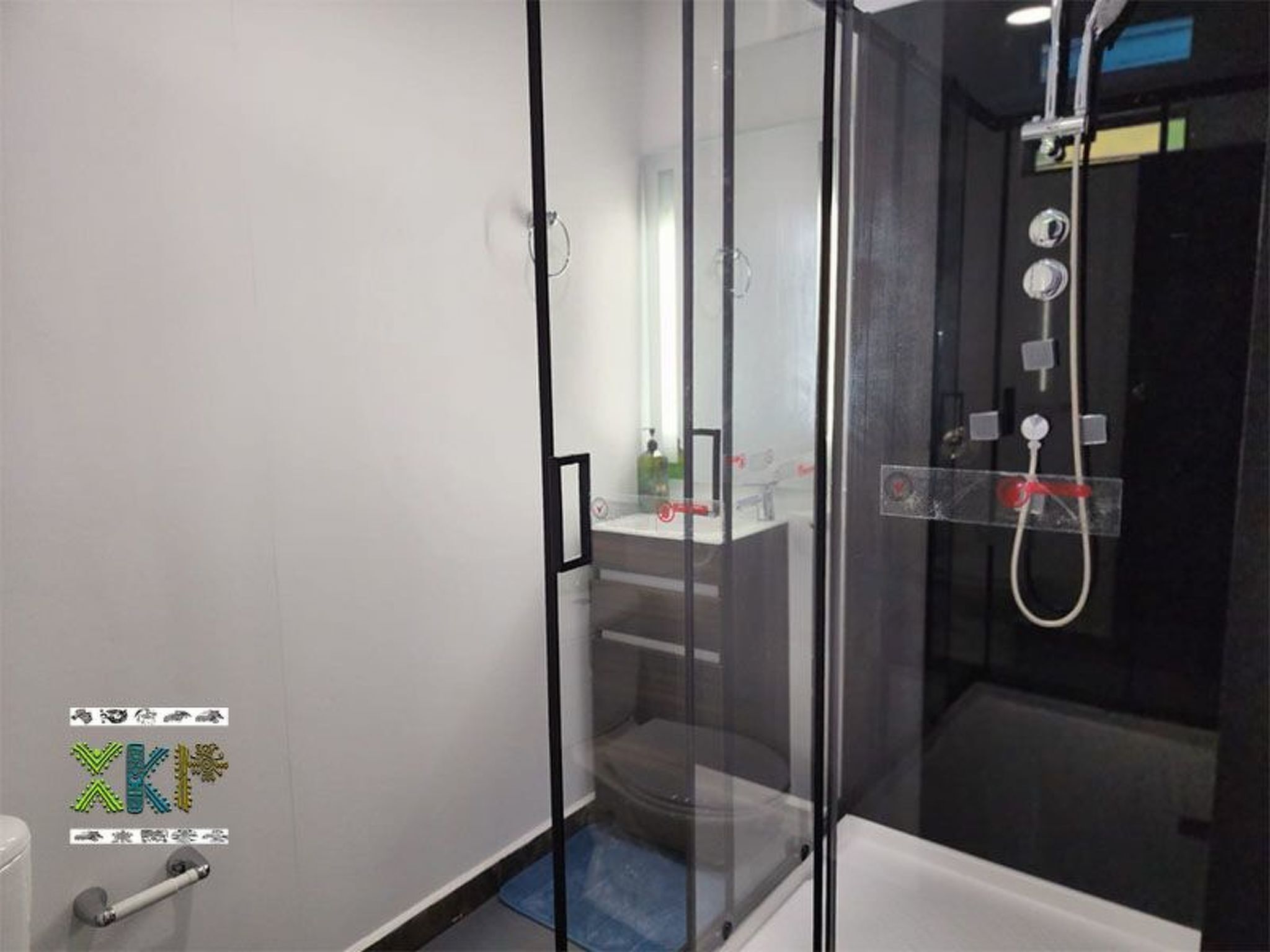 Un baño moderno con ducha de vidrio, lavamanos a la vista y un inodoro.