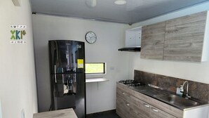 A compact kitchen with a refrigerator, stove, sink, and a clock on the wall. - Encanto Llanero by Interhome (Villavicencio Meta)