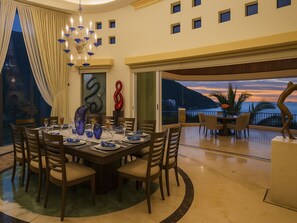 A dining area with a table set for six, surrounded by chairs, and a view of the sea at sunset. - Ferienvilla "Villa Armonia" mit Infinity Pool by Interhome (Boca de Tomatlan)