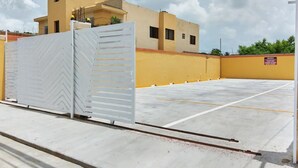 Un estacionamiento con acceso restringido y un edificio al fondo.