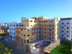Un hotel de varios pisos con balcones, un letrero que dice 'Aparthotel' y una entrada con portones.