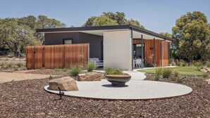 A modern house with a wooden fence, a circular seating area with a planter, and a well-maintained garden. - ESCAPE TO PICTURESQUE EAGLE BAY IN THIS BEAUTIFULLY APPOINTED 2 BED STUDIO (Eagle Bay)