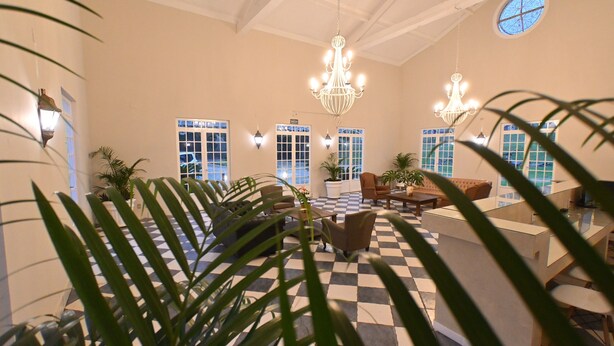 A lobby with checkered flooring, a chandelier, potted plants, and a seating area. - Quinta das Águas by Summit Hotels (Itapira)