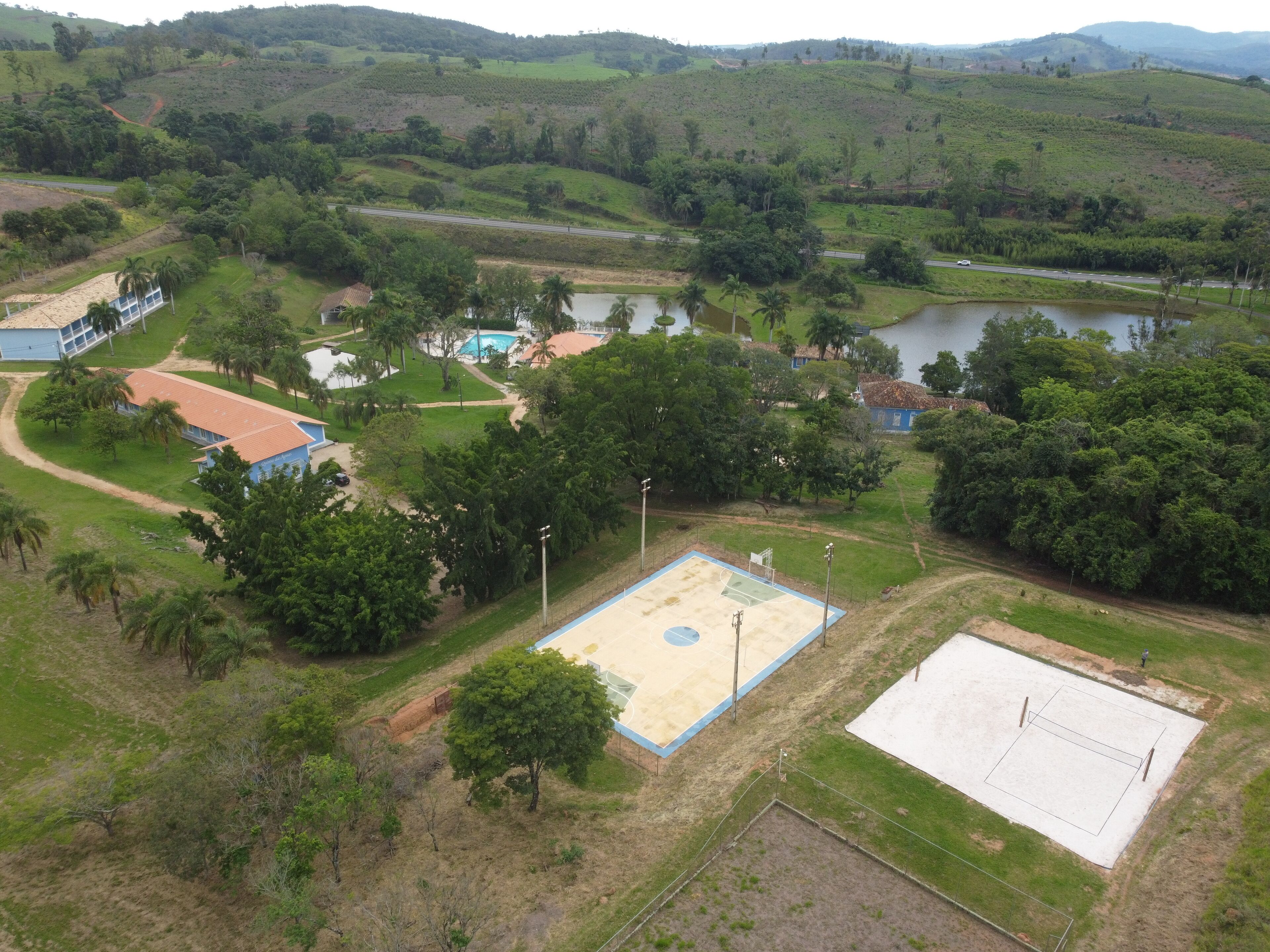 Vista aérea de una zona residencial con un espacio abierto amplio, una piscina y una cancha de baloncesto.