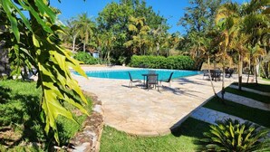 A swimming pool with a stone patio, surrounded by greenery and palm trees. - Quinta das Águas by Summit Hotels (Itapira)