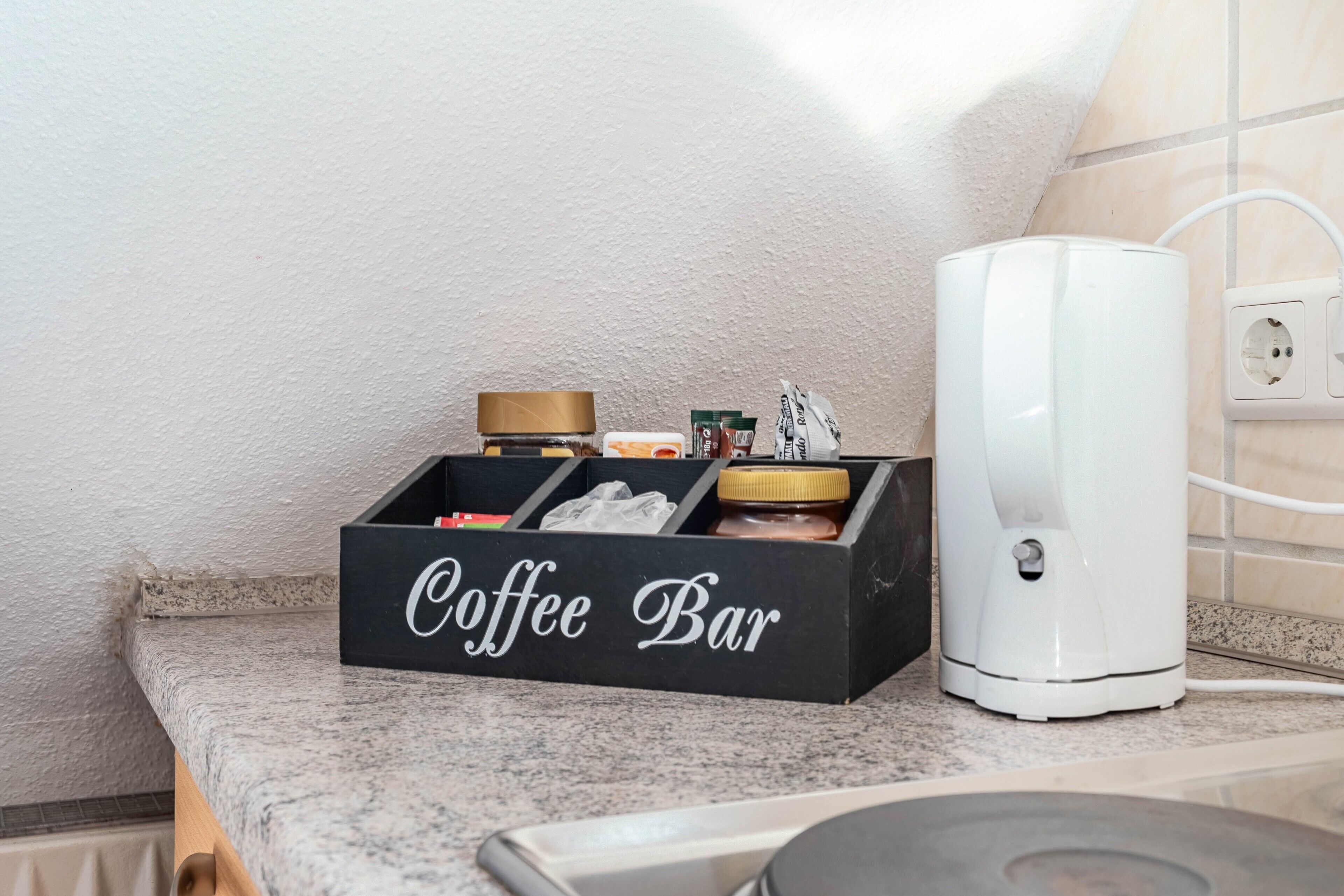 Un bar à café avec une machine à café et une boîte noire portant l’inscription « Bar à café », le tout posé sur un comptoir de cuisine.