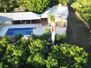 A residential property with a swimming pool, a covered patio, and a garden area with various plants.