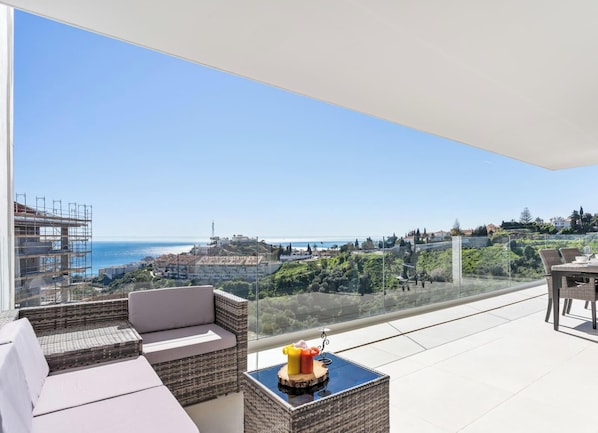 A balcony with a view of the sea and a cityscape, furnished with a sofa and a table with fruit. - Regalo | Sea view - terrace - pool (Fuengirola)