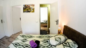 Un dormitorio con cama, una puerta, un cuadro y una lámpara.