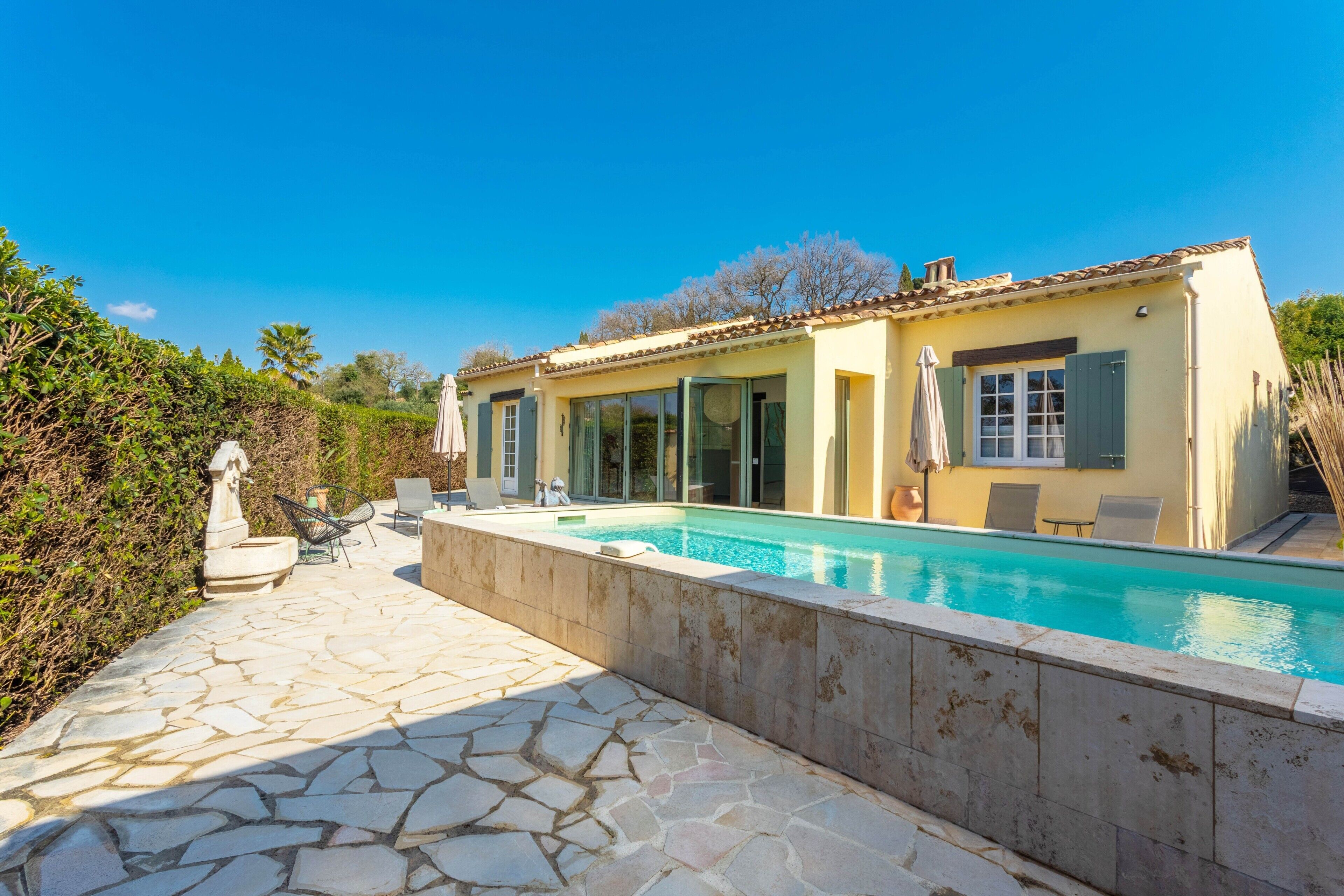 Ein Haus mit Swimmingpool, Steinterrasse und Sitzgelegenheit im Freien.